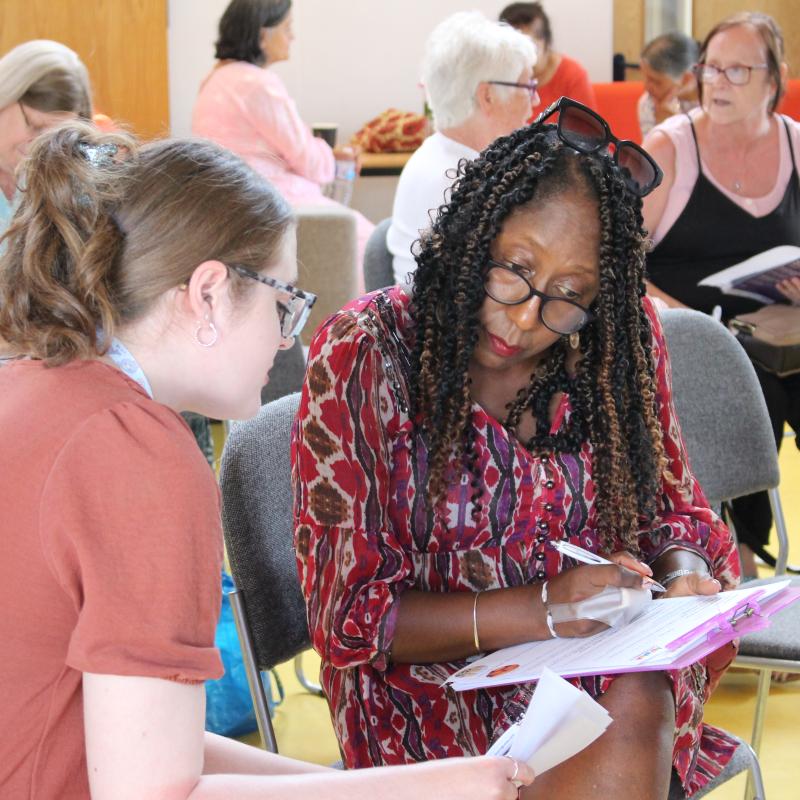 a member of staff helping a lady fill in a form