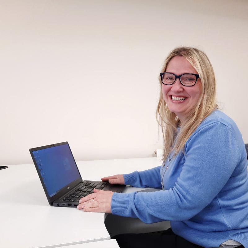 Paola smiling at her desk.