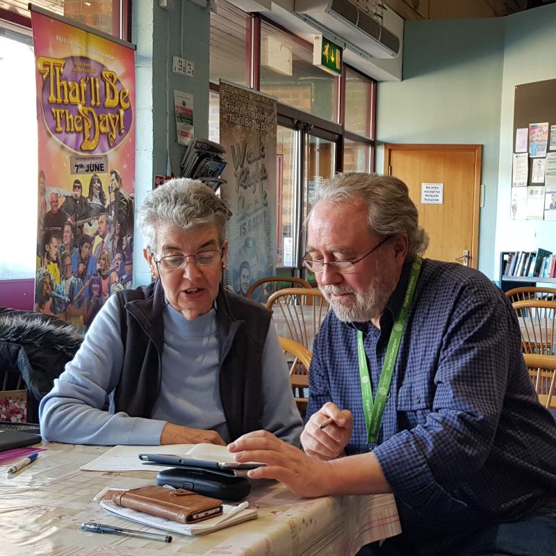 Two elderly individuals looking at a tablet in a comfortable environment.