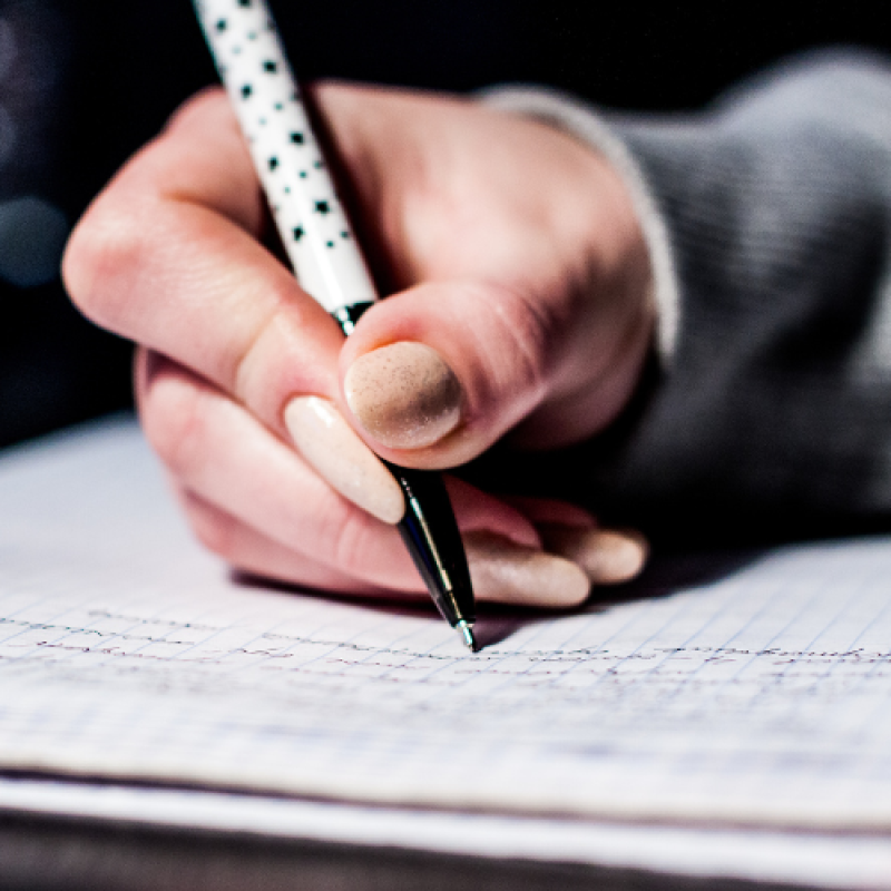Somebody writing with a pen on a piece of paper in a closeup.