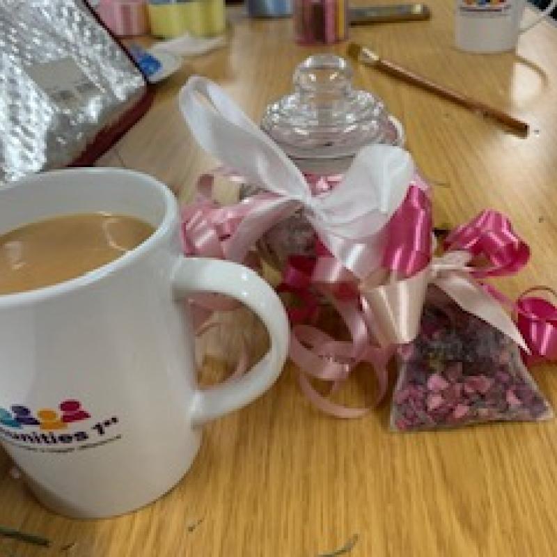 Mug of tea on a table next to some arts and crafts things